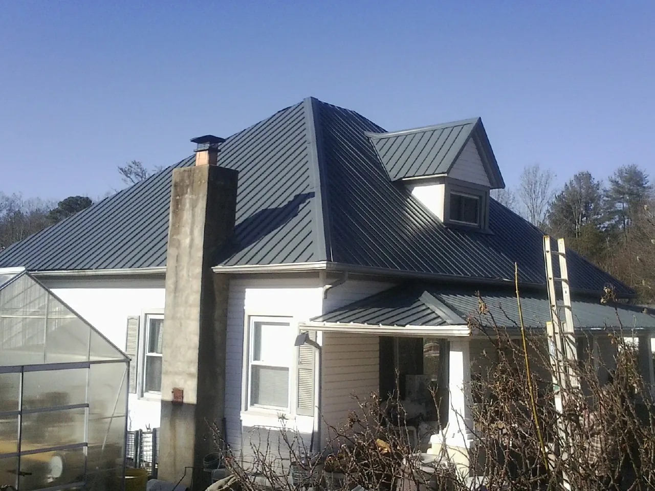 Dark blue standing seam metal roof on a white farmhouse with dormer — Slate & Tile Roof Repair by Roofing Brothers in Burr Oak