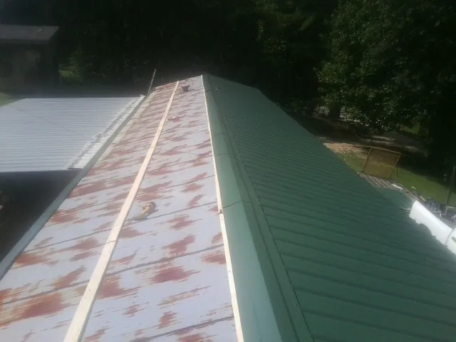 Old rusted panels beside newly installed green metal roofing — Wind Damage Roof Repair by Roofing Brothers in Burr Oak