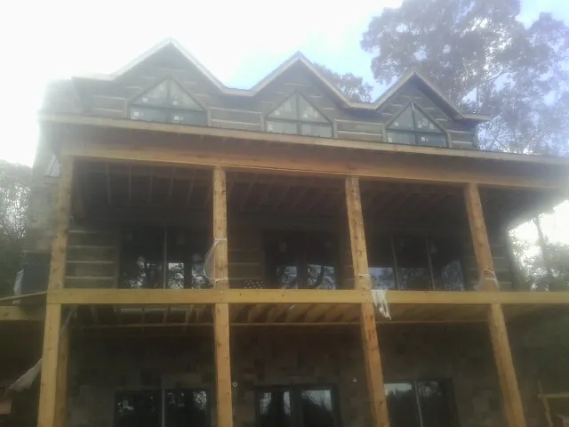 Dormers and porch framing on a large log home under construction — Roof Coating work by our crew in Burr Oak