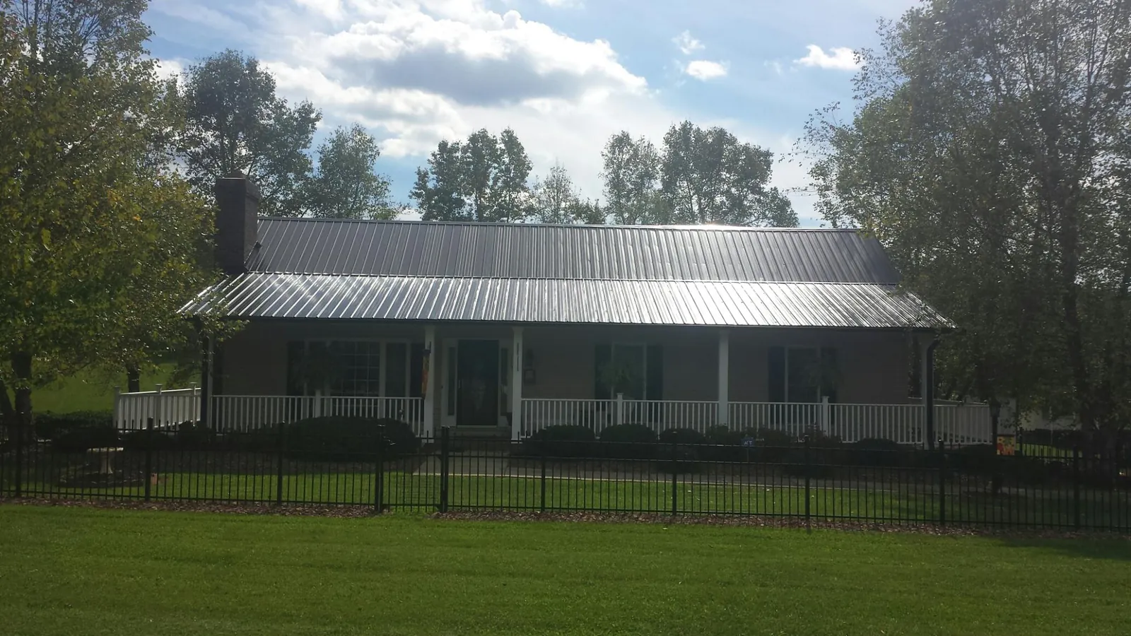 Gray metal roof on a brick ranch with a full width front porch — Gutter Guard Installation work by our crew in Burr Oak