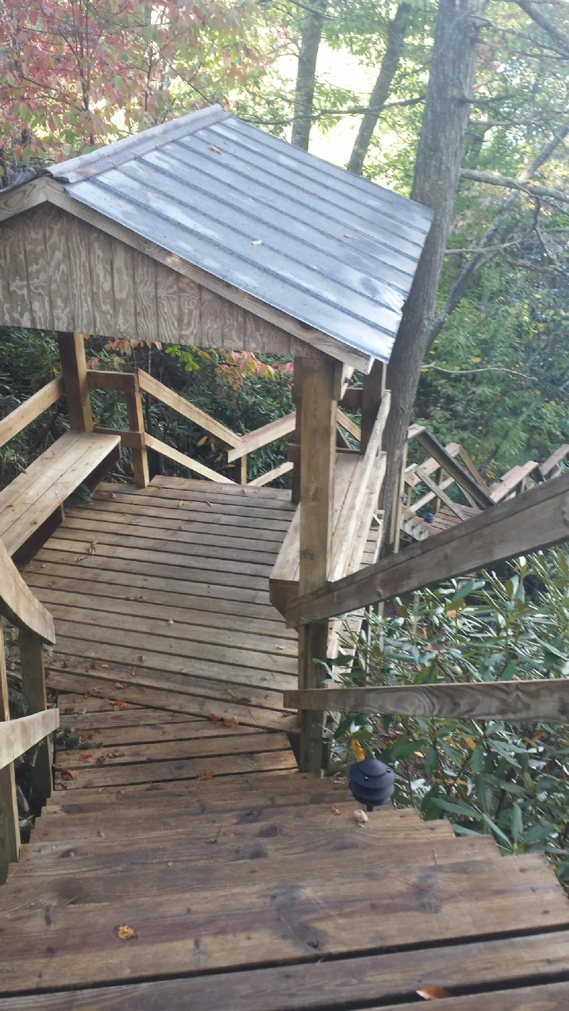 Metal roofed shelter over wooden steps on a wooded walkway — Skylight Repair & Installation work by our crew in Burr Oak