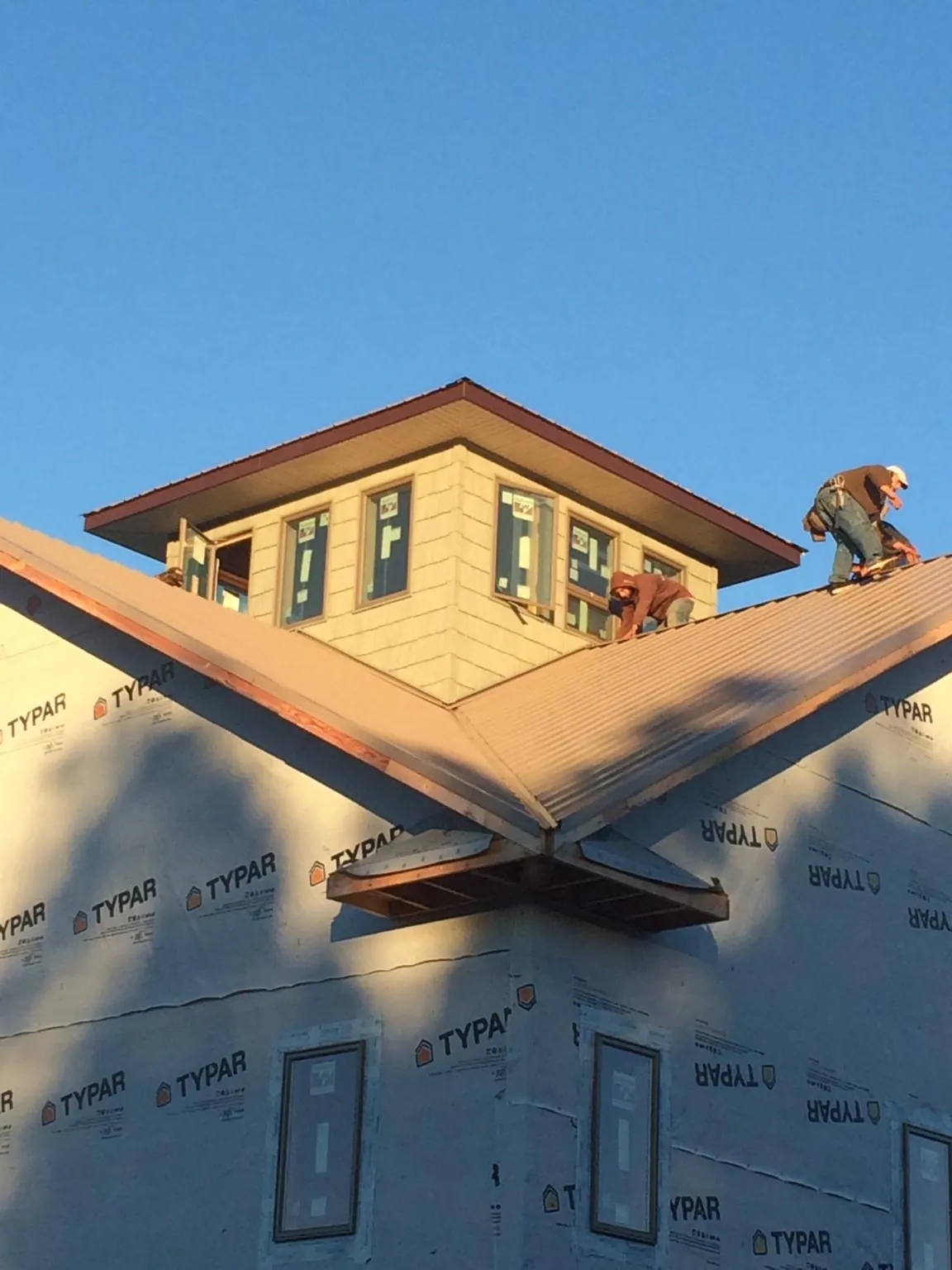 Roofers working around a rooftop cupola on a new metal roof at sunset — Roof Waterproofing in Burr Oak by Roofing Brothers